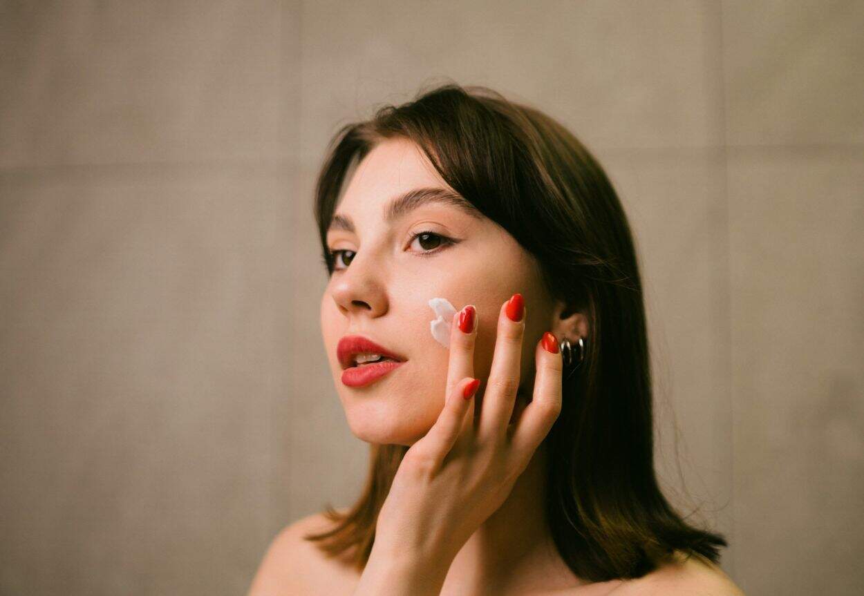 A woman putting cream on her face.