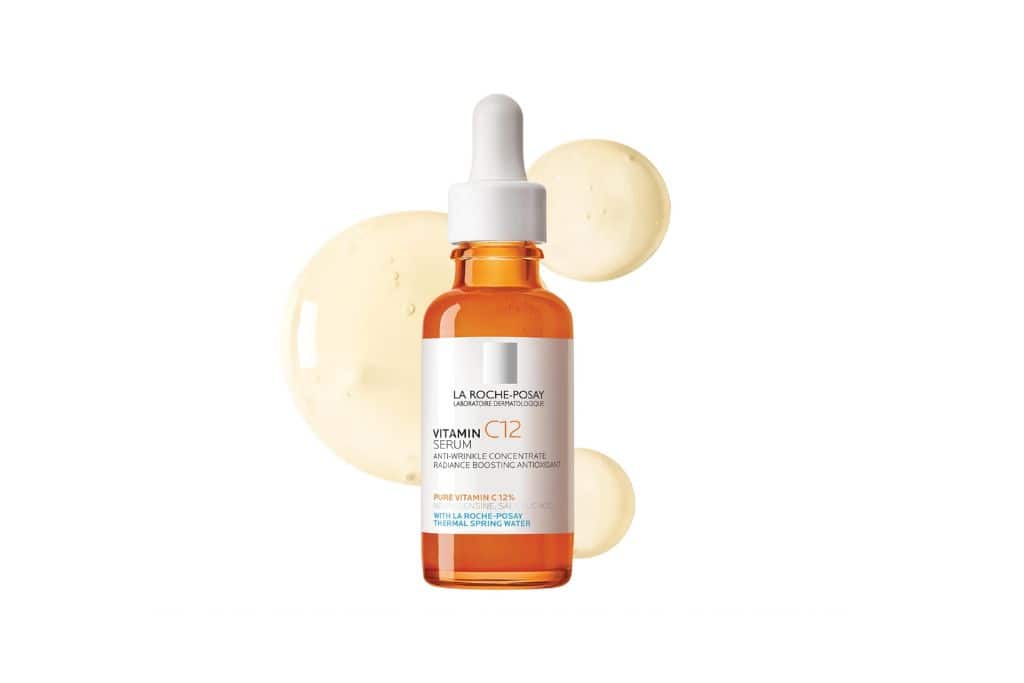 A bottle of orange serum with a white dropper top. 